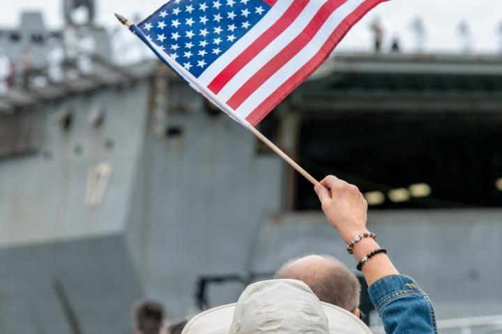 Woman Waving American Flag at Navy Ship