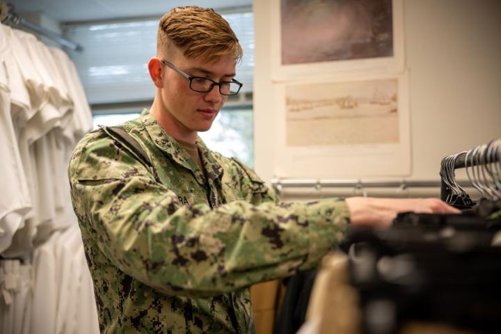 Service member looks through rack of uniforms