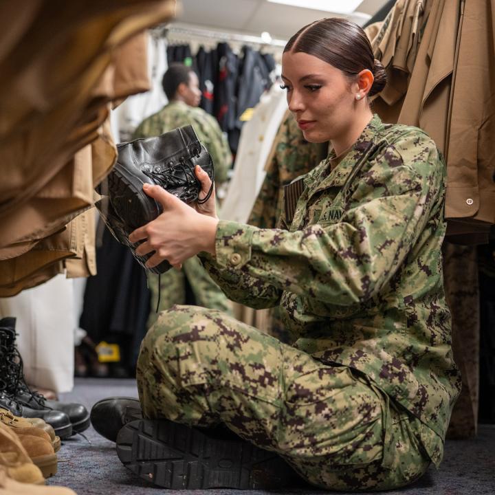 Female Sailor sitting on the floor looking at uniform boots